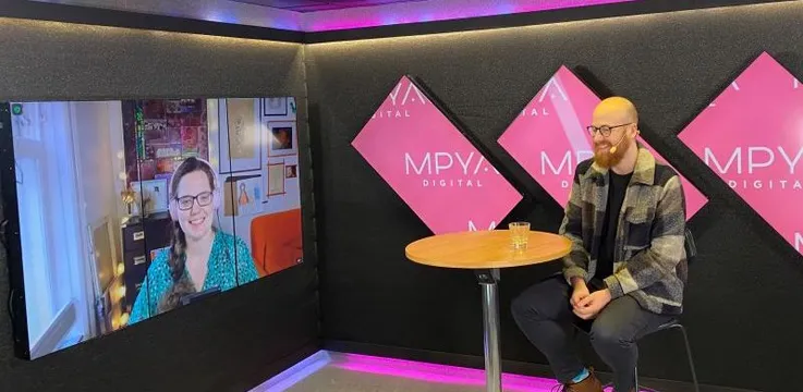 Queen Raae on a big screen in the MPYA Digital studio, talking with the host